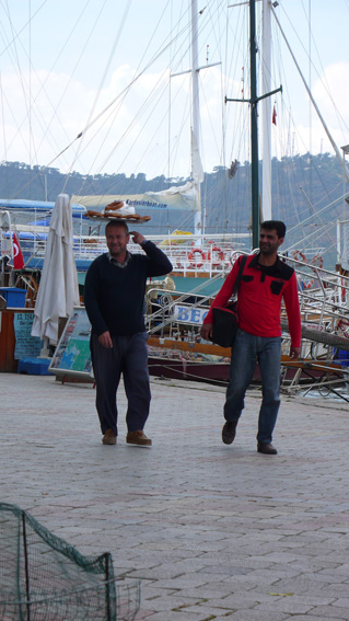 Bread-sellers with tray of fresh pretzels on his head, walking along Fethiye harbour