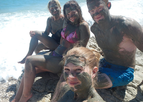 Four people sitting on rock covered in mud; softend the skin